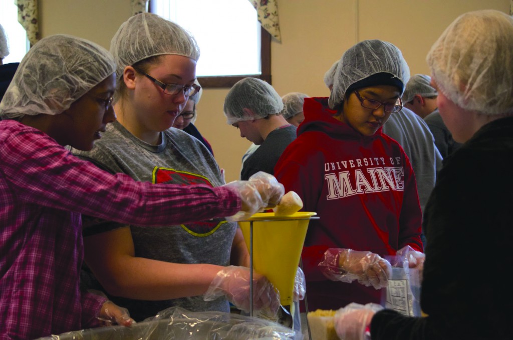 University of Maine students Sierra Crosby, Brigitte Parady, and Aliya Uteuova help pack some of the 20,000 meals to be distributed in the Greater Bangor area for the MLK day of service in Old Town this past weekend. 
